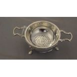 An Elizabeth II silver twin handled tea strainer, Birmingham 1963, of Georgian design,