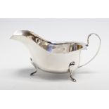 A George V silver plain oval shaped sauce boat, wavy rim on three scoll and hoof feet, E Viner,