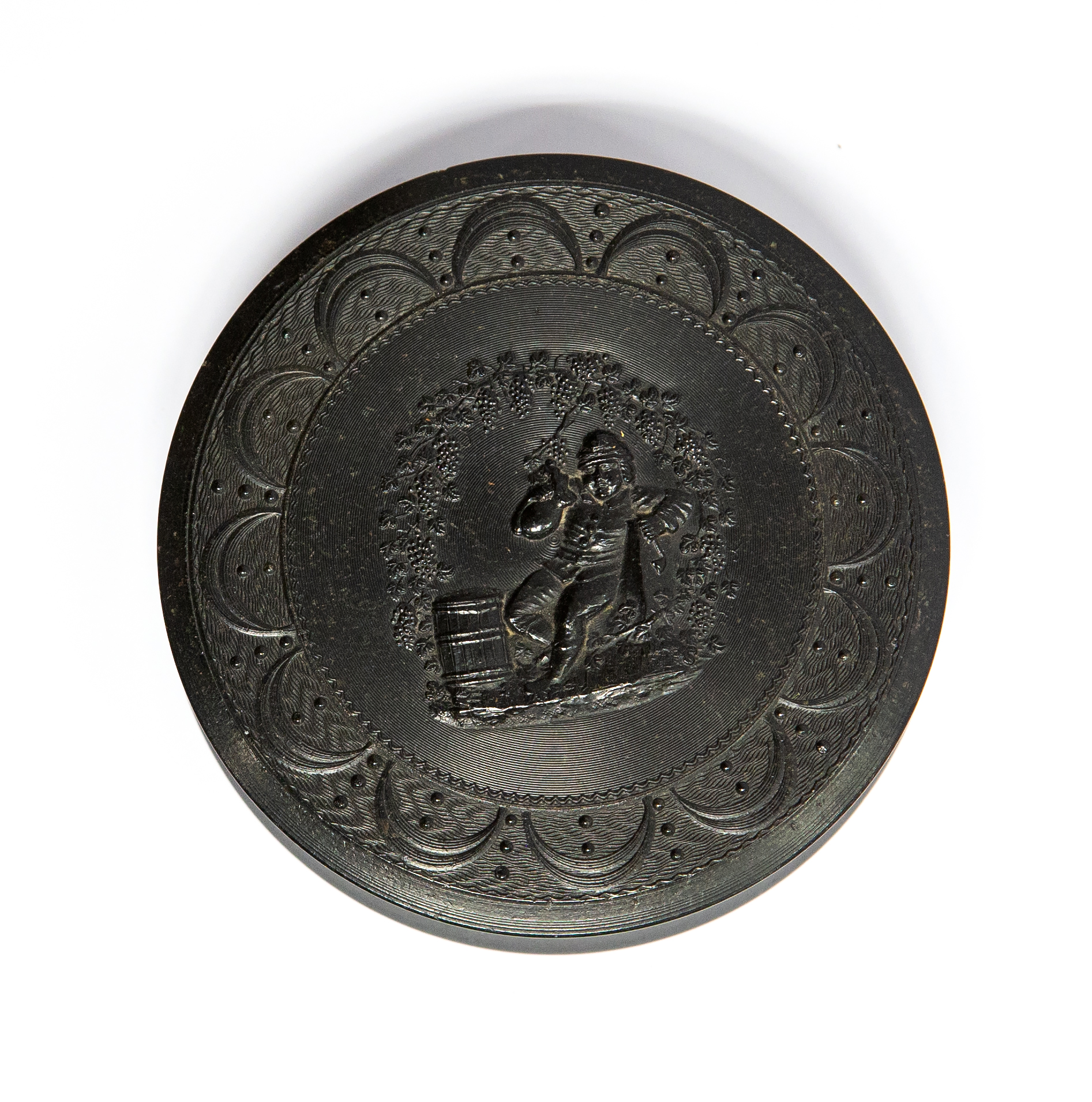 A 19th Century circular pressed horn snuff box, the cover with a figure of a man drinking ale,