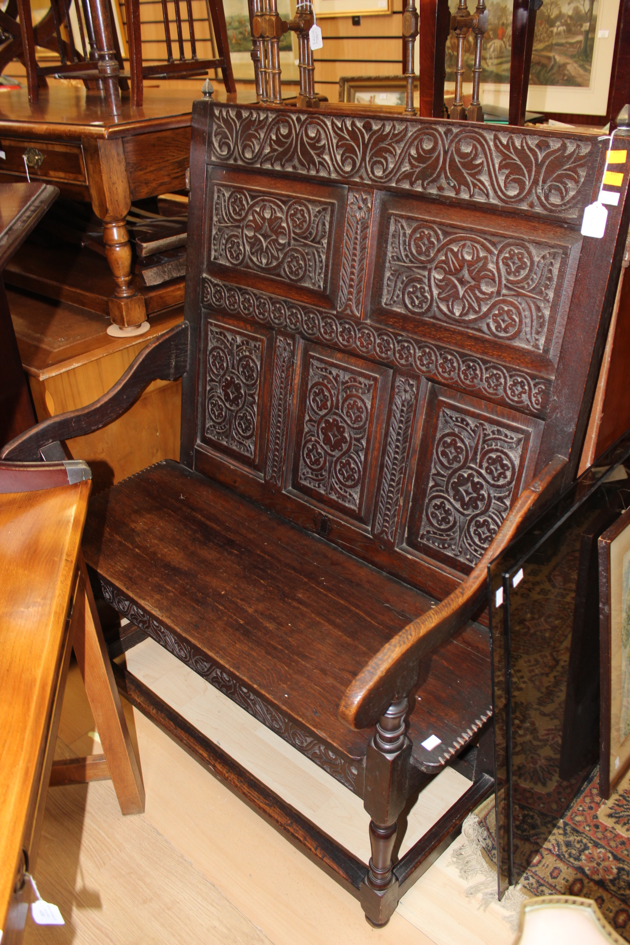 A Victorian oak joined settle, carved panels to back, downswept arms, plank seat,