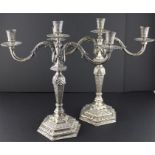 A pair of Islamic white metal three branch candelabra, the stems engraved with foliage and