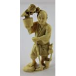 A Japanese Meiji period carved ivory okimono, of a man with walking stick carrying a pot of flowers,