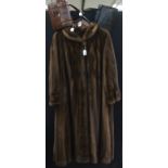 A full length mid brown Mink coat with a cowl collar and a Mink button fastening.