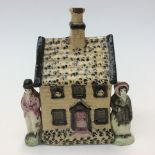 An early Staffordshire money box in the form of a cottage