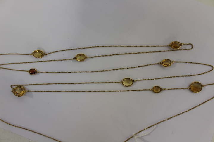 A long yellow metal chain with faceted citrine style stones