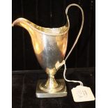 A George III silver helmet shaped cream jug, on square foot, C-scroll reeded handle and rim,