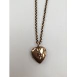 A 9ct rose gold heart shaped locket set to the front with seed pearl and red stone details,