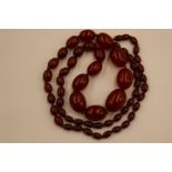 A string of graduated cherry amber coloured beads, all ovoid form, the largest 2.9cm long x 2.