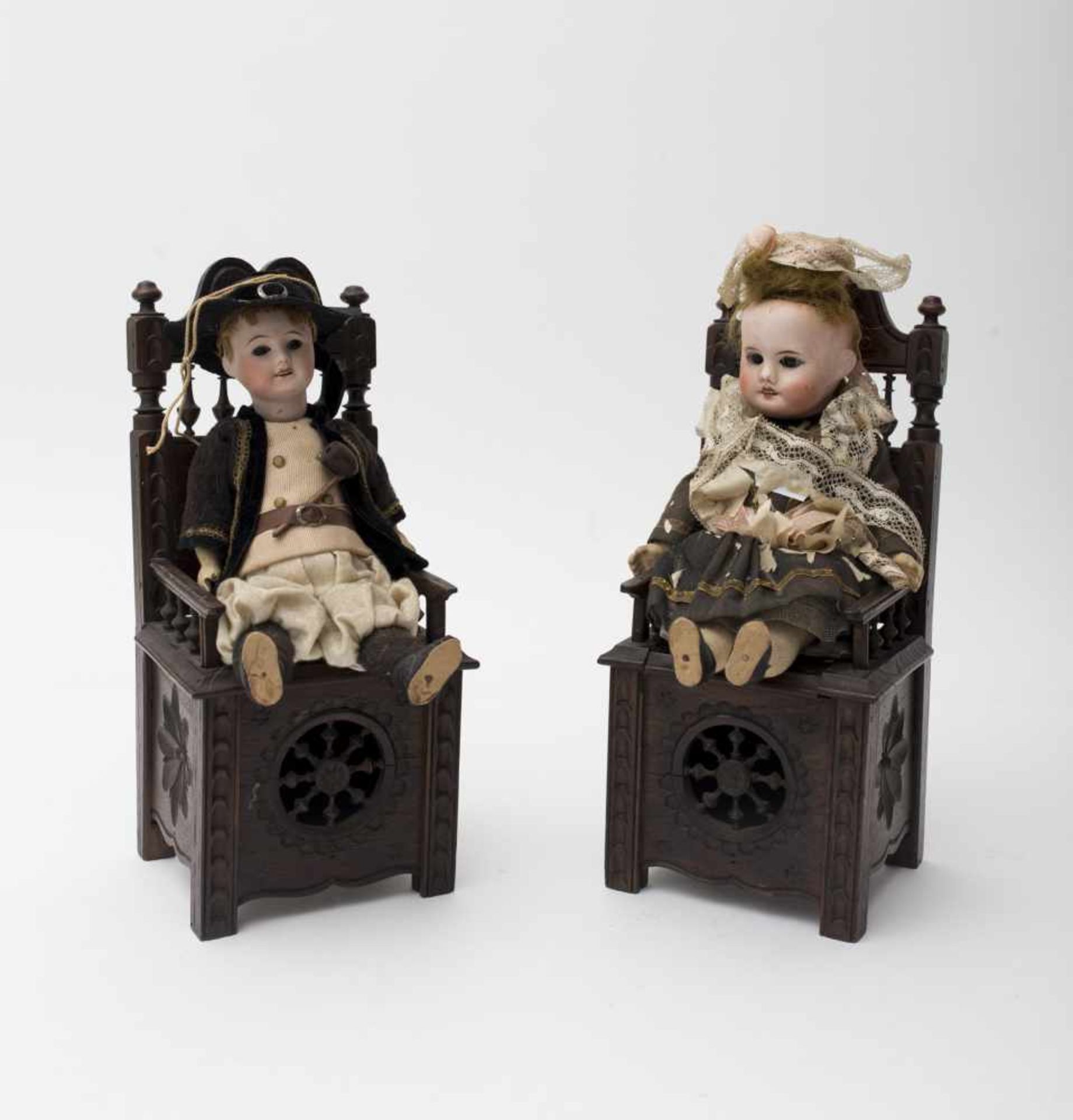 Two Breton dolls With biscuit head, open mouth, girl and boy, shown on two Breton chest seats, H=