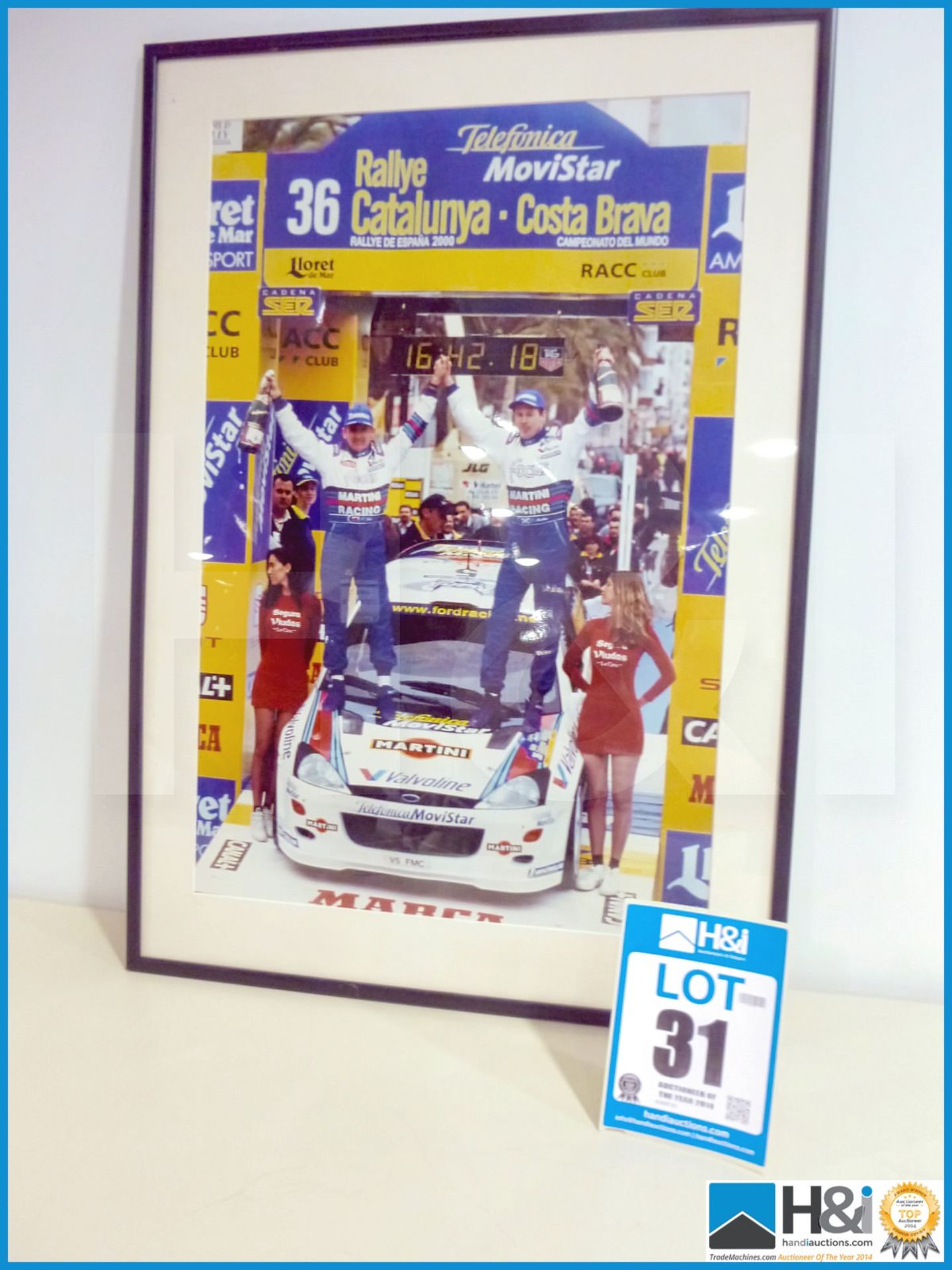 Framed print of Colin McRae and Nicky Grist Catalunya podium win. Appx 21in X 29in -- MC:N/A CILN:N/