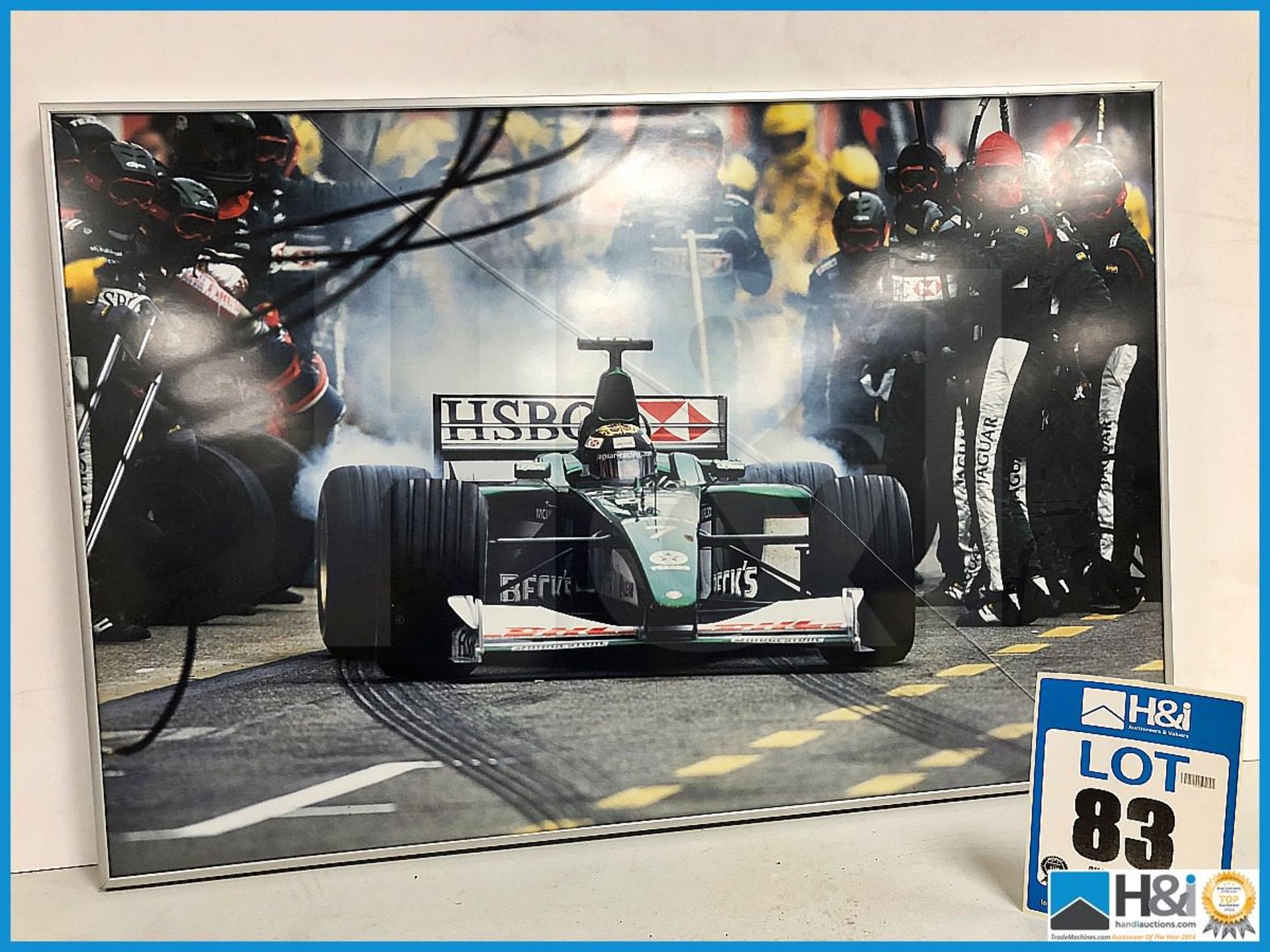 Ex Cosworth works framed print of F1 car leaving pits. Approx 30in x 20in. Crack in glass. Aluminium