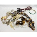 A quantity of costume jewellery including amber style beads, bracelets, brooches, buckles, stone