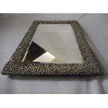 A rectangular bevelled dressing table mirror in a pierced silver frame with leaf scroll decoration -