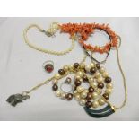 A row of cultured pearls with silver clasp, freshwater pearls with gold clasp, coral beads, two jade