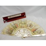 A French hand painted fan by J Duveilory with mother of pearl sticks and guards, on in a red