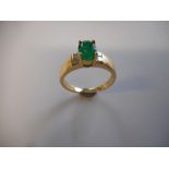 A lady's ring set centre emerald with two Princess cut diamonds to each shoulder, on an 18ct. gold