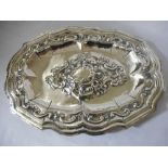 A Spanish silver coloured metal tray of shaped oval form with raised leaf scroll decoration to the