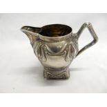 A Russian silver cream jug in the Art Nouveau style with flowers, shaped handle, on square base -