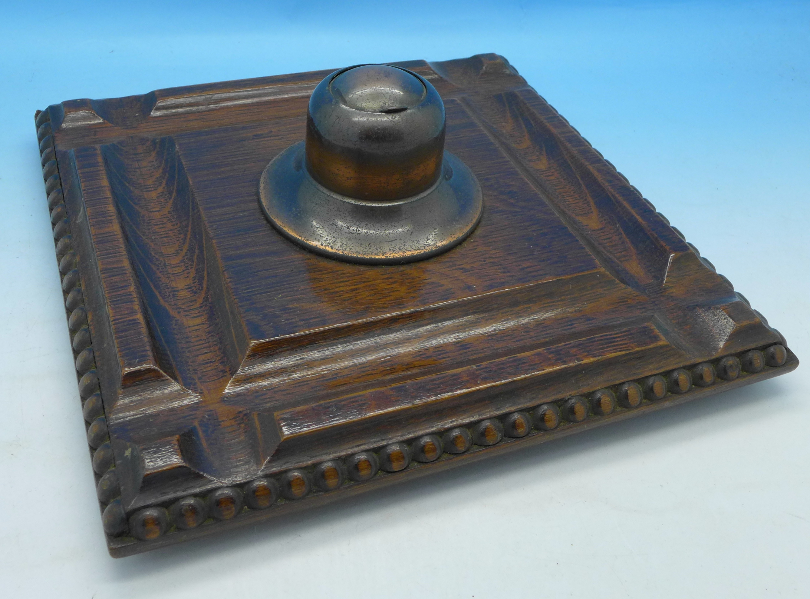 An Edwardian oak and copper inkwell and pen stand