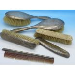 Four silver backed brushes and a comb,