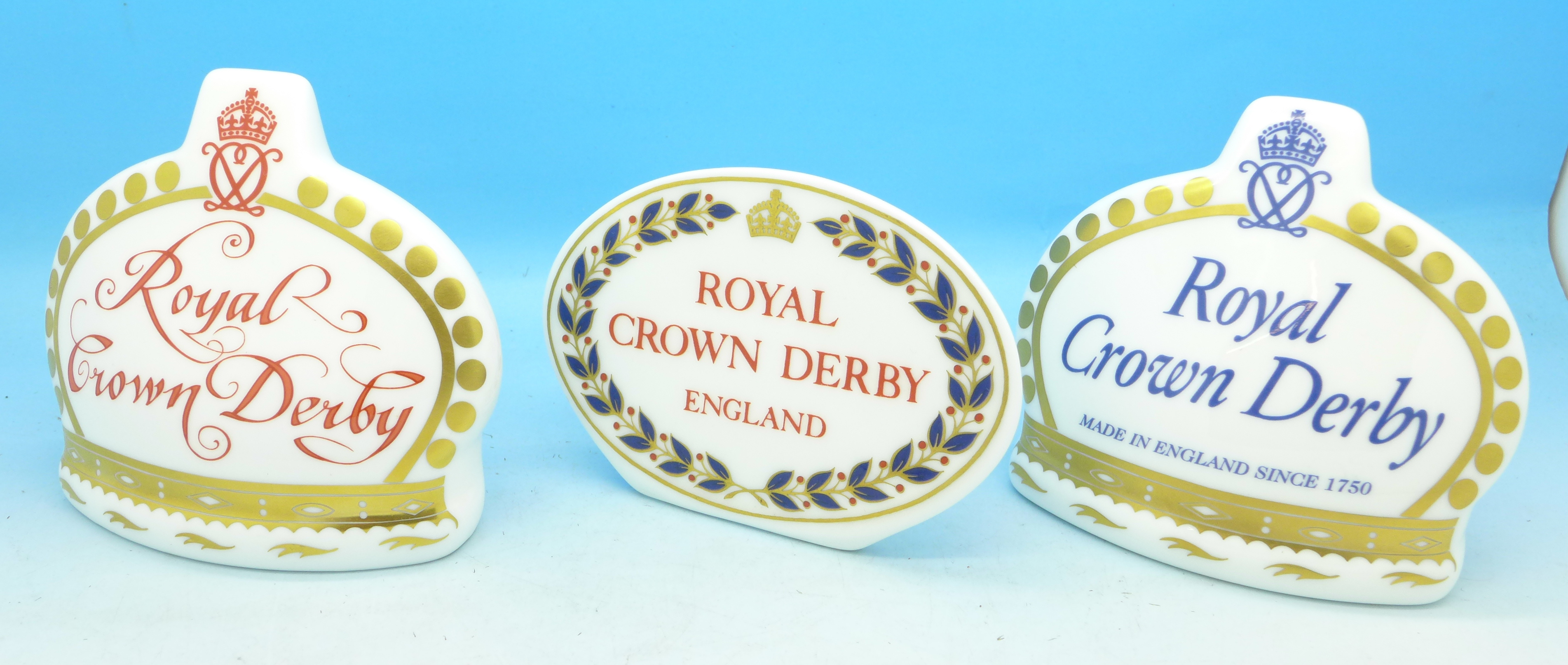 Three Royal Crown Derby advertising plaques, two with gold stoppers,