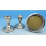 A pair of silver candlesticks and circular silver photograph frame,