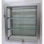 A lockable aluminium glazed table top cabinet with sliding doors