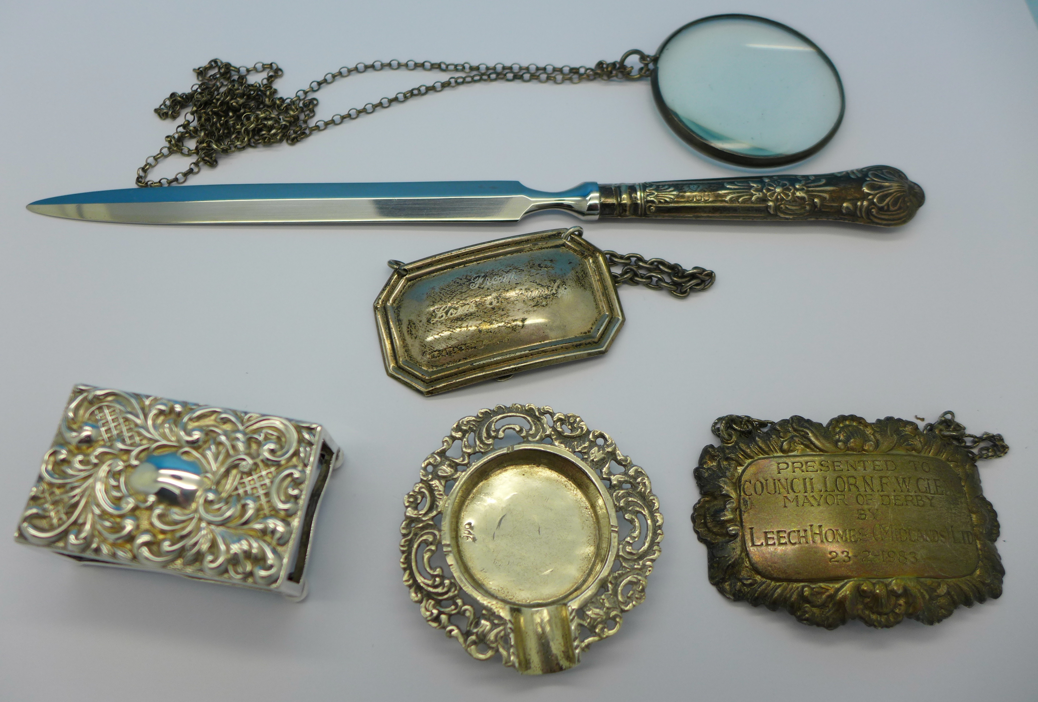 Five silver items; a silver handled letter opener, eye glass, two labels with inscriptions,