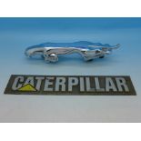 A Jaguar car mascot and a metal Caterpillar badge