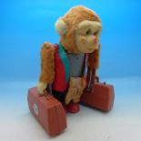 A Japanese Yano Man Toys battery operated chimpanzee carrying two suitcases,