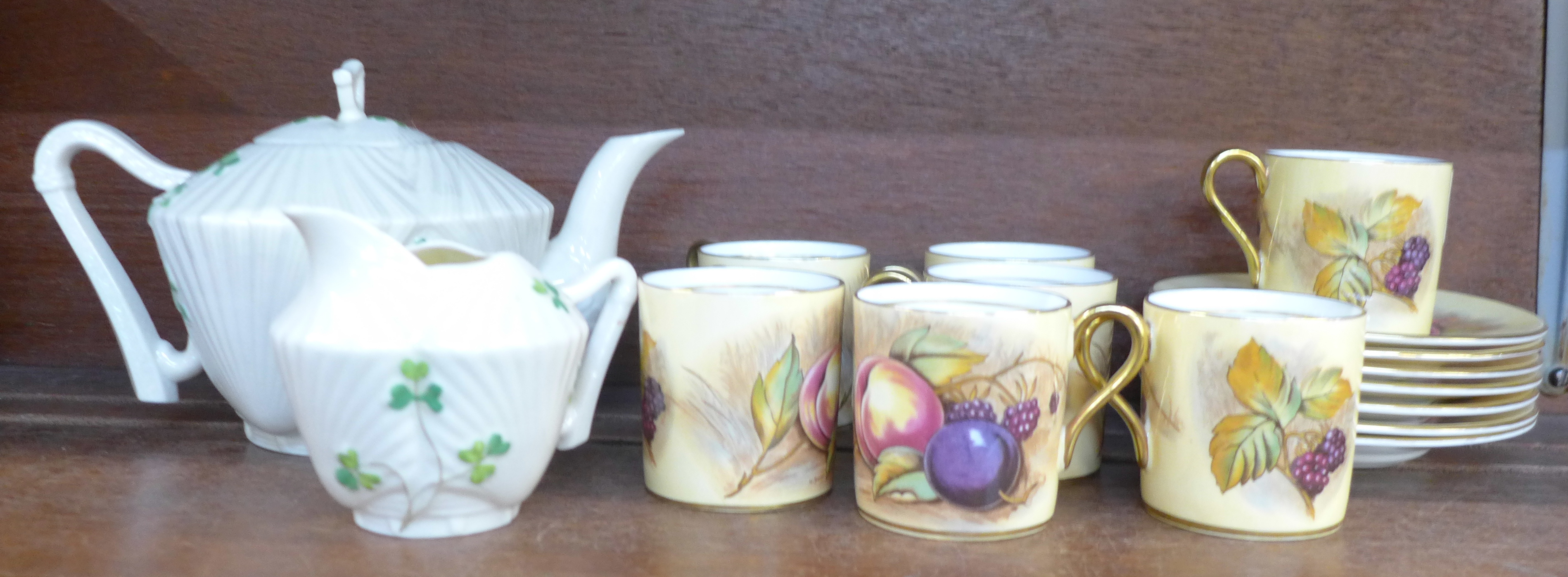 Seven Aynsley coffee cans and saucers decorated with fruit and a Belleek teapot and cream jug,