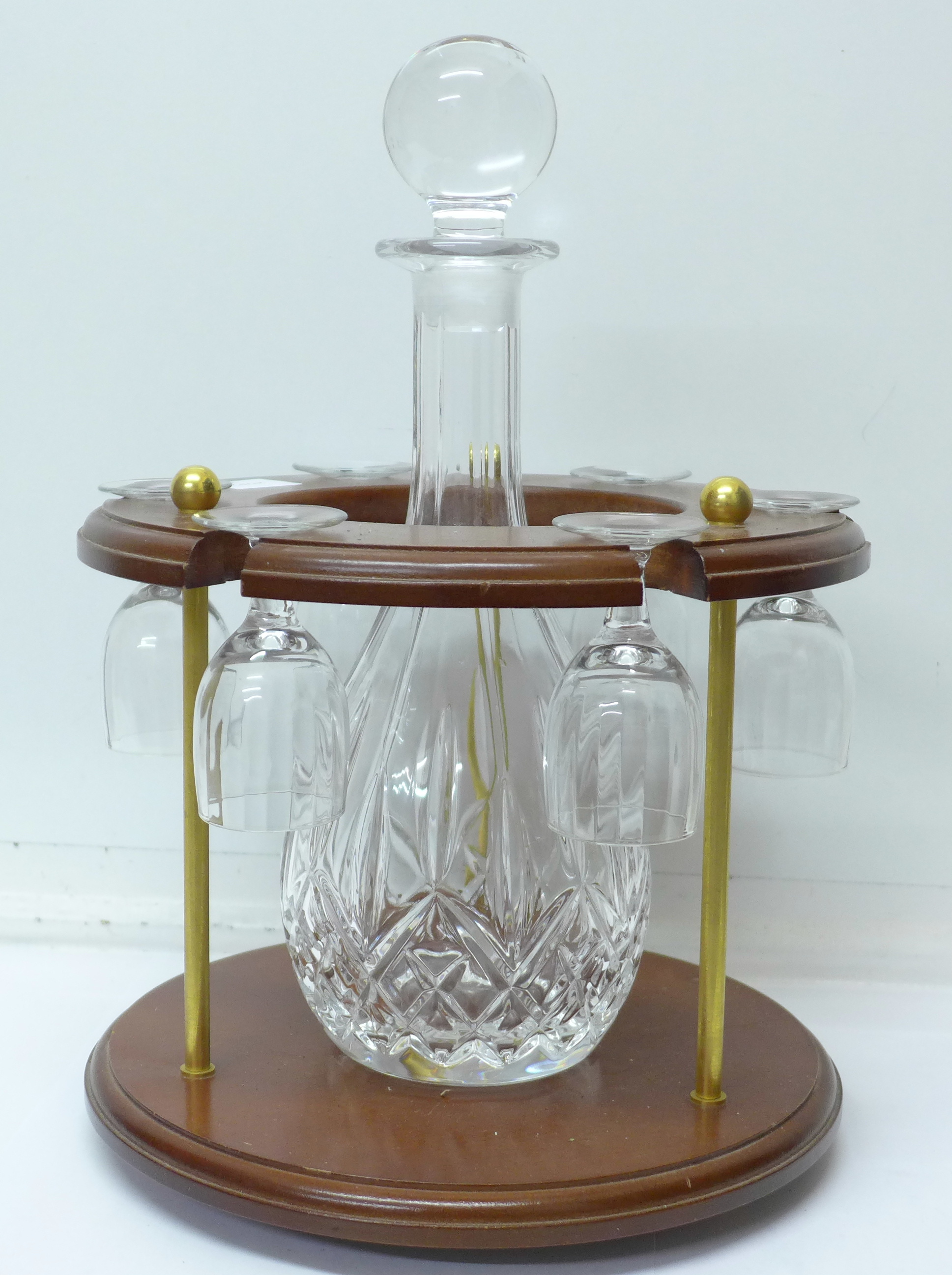 A glass decanter with six glasses on a wooden base,