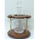 A glass decanter with six glasses on a wooden base,