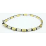 An 18ct yellow and white gold designer bracelet set on rubber marked 750, 13.