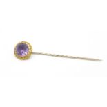 A yellow metal and amethyst stick pin