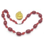 A gilt metal portrait locket and a red coloured bead necklace