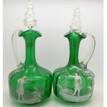 A pair of green glass Mary Gregory jugs with stoppers