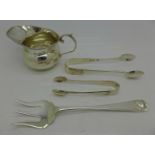 Two pairs of silver sugar bows, a silver jug and a silver bread fork,