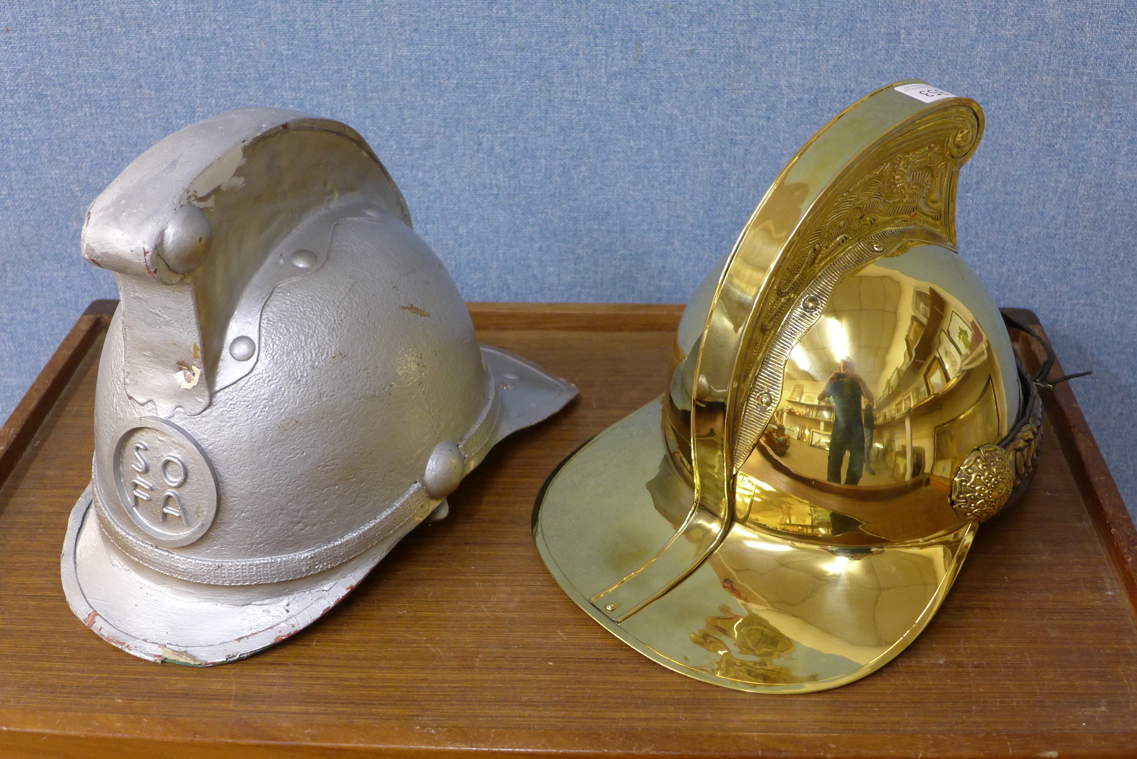 A replica brass fire brigade helmet and a papier mache helmet