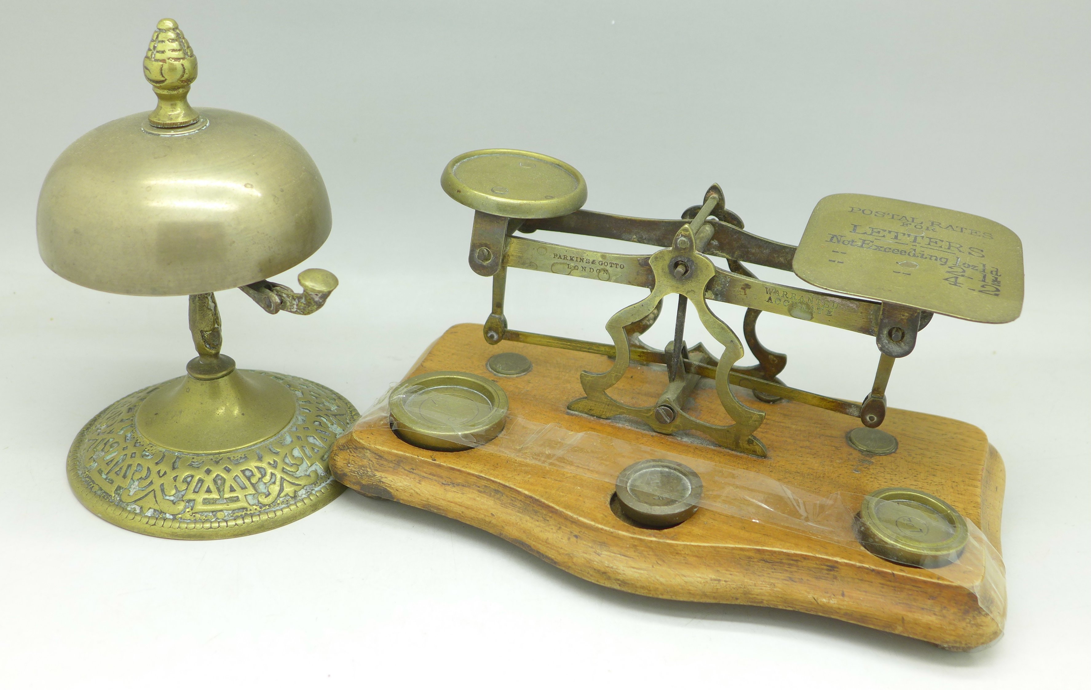 A set of postal scales marked Parkins & Gotto and a brass desk bell