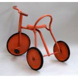 An orange painted childrens tricycle.