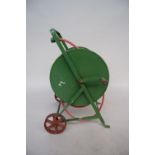 A vintage green painted metal hose winder with cast iron wheels and wooden handle and later garden