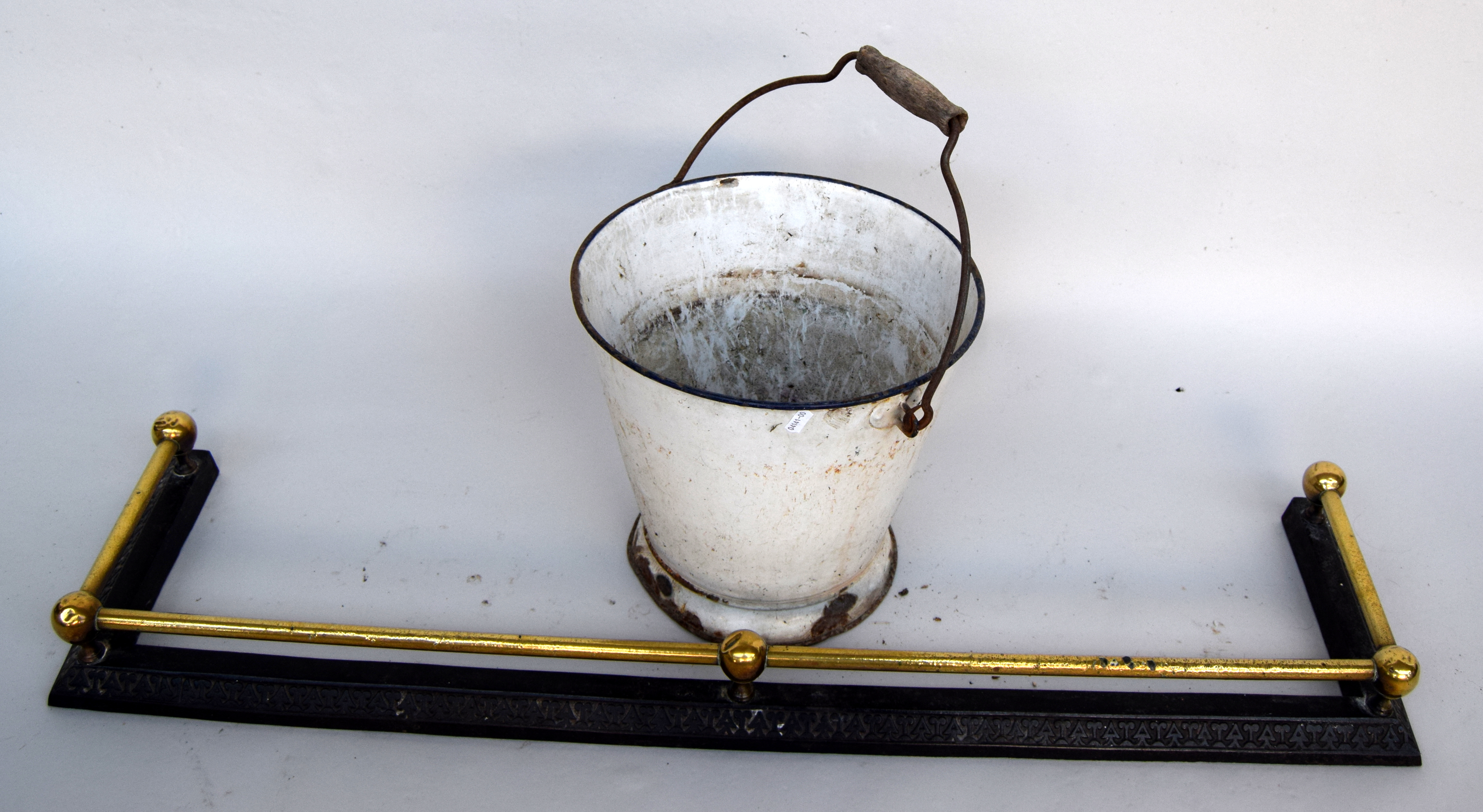 A brass and cast iron fender 102cmL together with a vintage white enamel bucket with blue rim