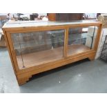 An Art Deco haberdashers glazed display cabinet with sliding doors, single shelf and brass rule,