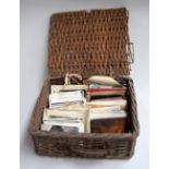 A wicker hamper containing a number of used and unused vintage postcards with a variety of subjects