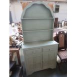 A green painted pine dresser with domed top over two drawers and a cupboard base,