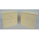 A pair of cream painted bedside tables each consisting of two drawers