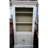 A painted pine bookshelf over cupboard doors,