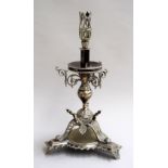 A late 19th century EPNS gothic candlestick, raised on pierced legs finishing in scrolls,