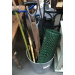 A galvanised metal dustbin containing garden tools and a galvanised metal compost bin